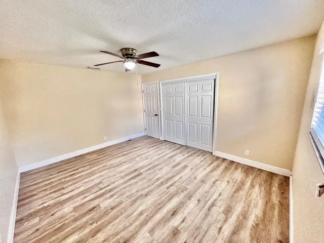 a view of empty room with wooden floor and fan