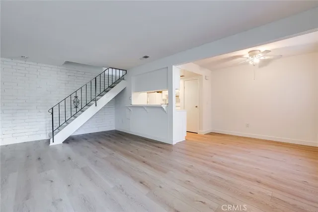 a view of an empty room with wooden floor and stairs