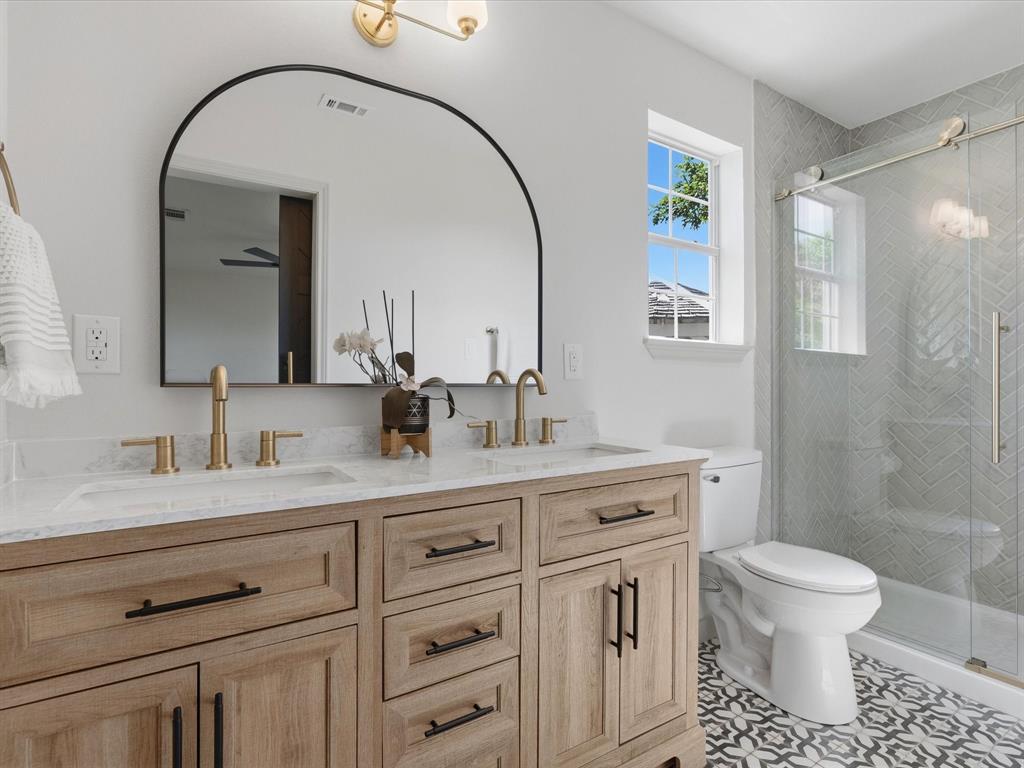 289 County Road 4655 Rhome, TX 76078 - Photo 11 of 34 Dual vanity featuring light wood-finish cabinetry, white countertops, and gold-toned fixtures