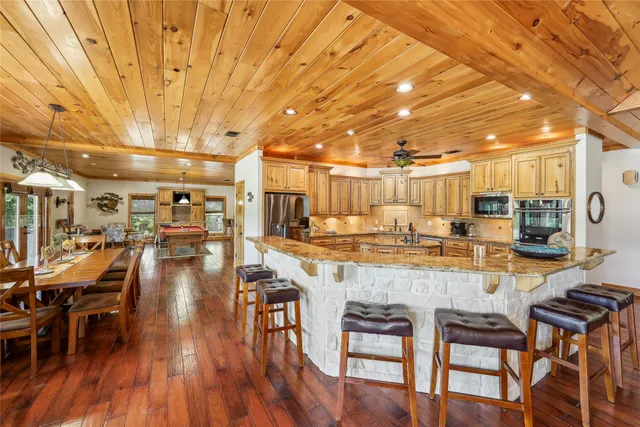 a dining hall with stainless steel appliances a dining table and chairs with wooden floor