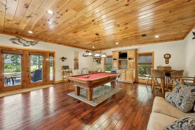 a living room with furniture a wooden floor and pool table