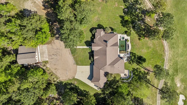 an aerial view of a house with a yard and trees all around
