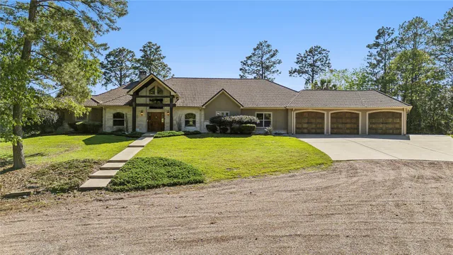 a view of a white house with a yard plants and large tree