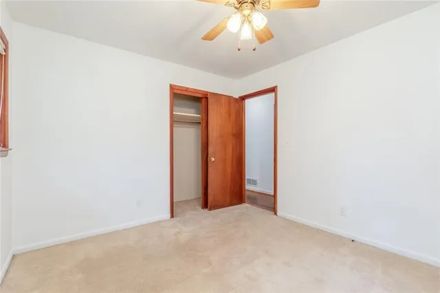 an empty room with a chandelier fan and closet