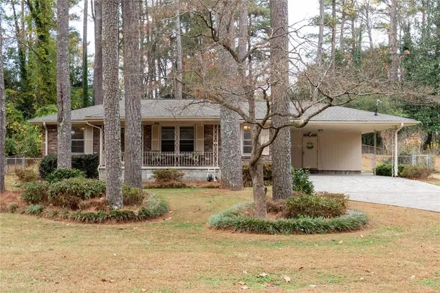 a front view of a house with garden and trees