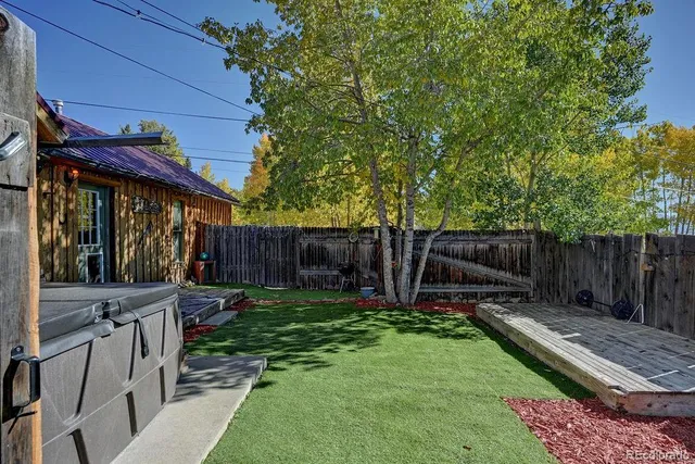 a view of a backyard with wooden fence and a large tree