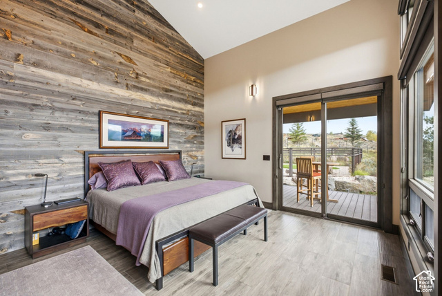 1130 Pace Road Park City, UT 84098 - Photo 34 of 73 Vaulted ceiling with wood-clad accent wall, large sliding glass door with outdoor access, and wood-finish flooring