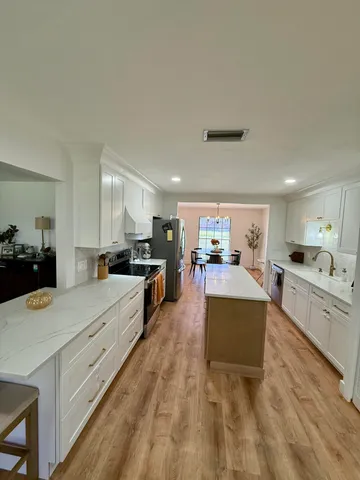 a large white kitchen with cabinets a sink and a stove
