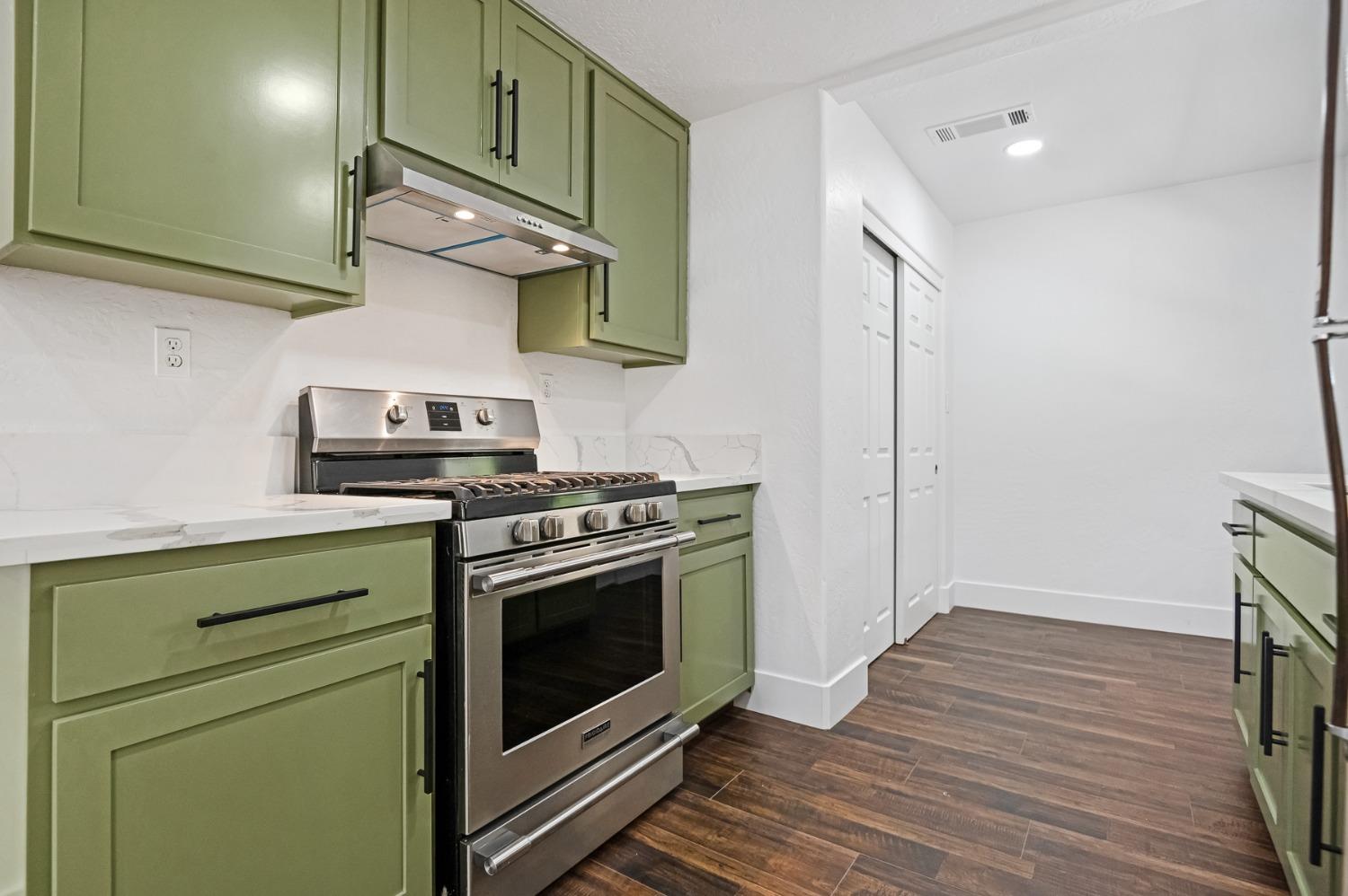 325 West Bush Street Lemoore, CA 93245 - Photo 37 of 55 a kitchen with stainless steel appliances wooden floor sink and a stove top oven