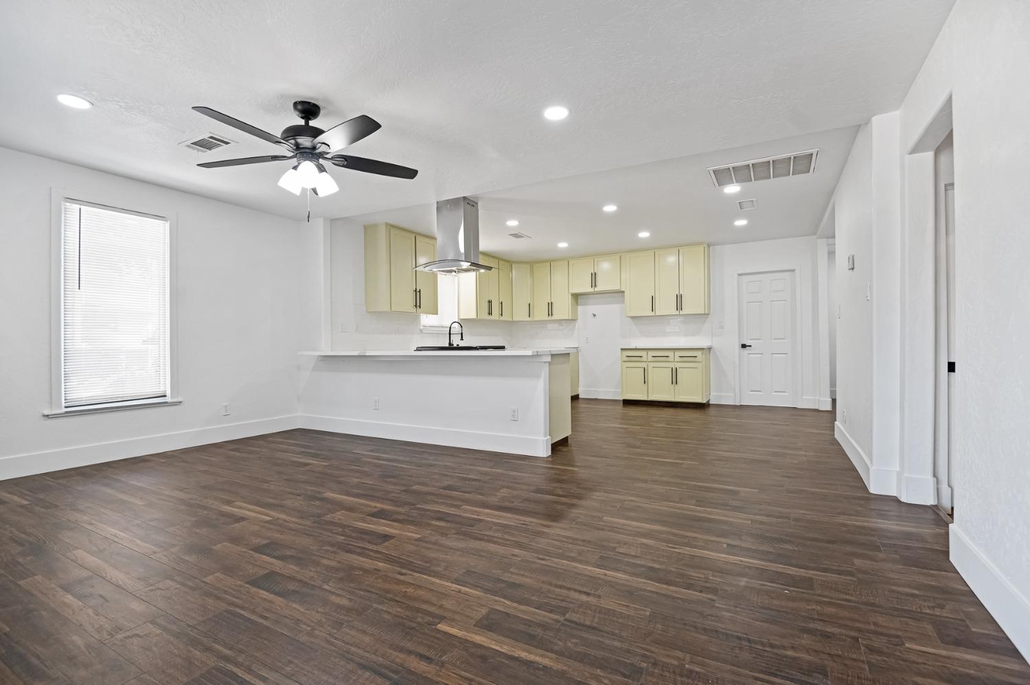325 West Bush Street Lemoore, CA 93245 - Photo 6 of 55 a view of an empty room and kitchen with wooden floor and a window