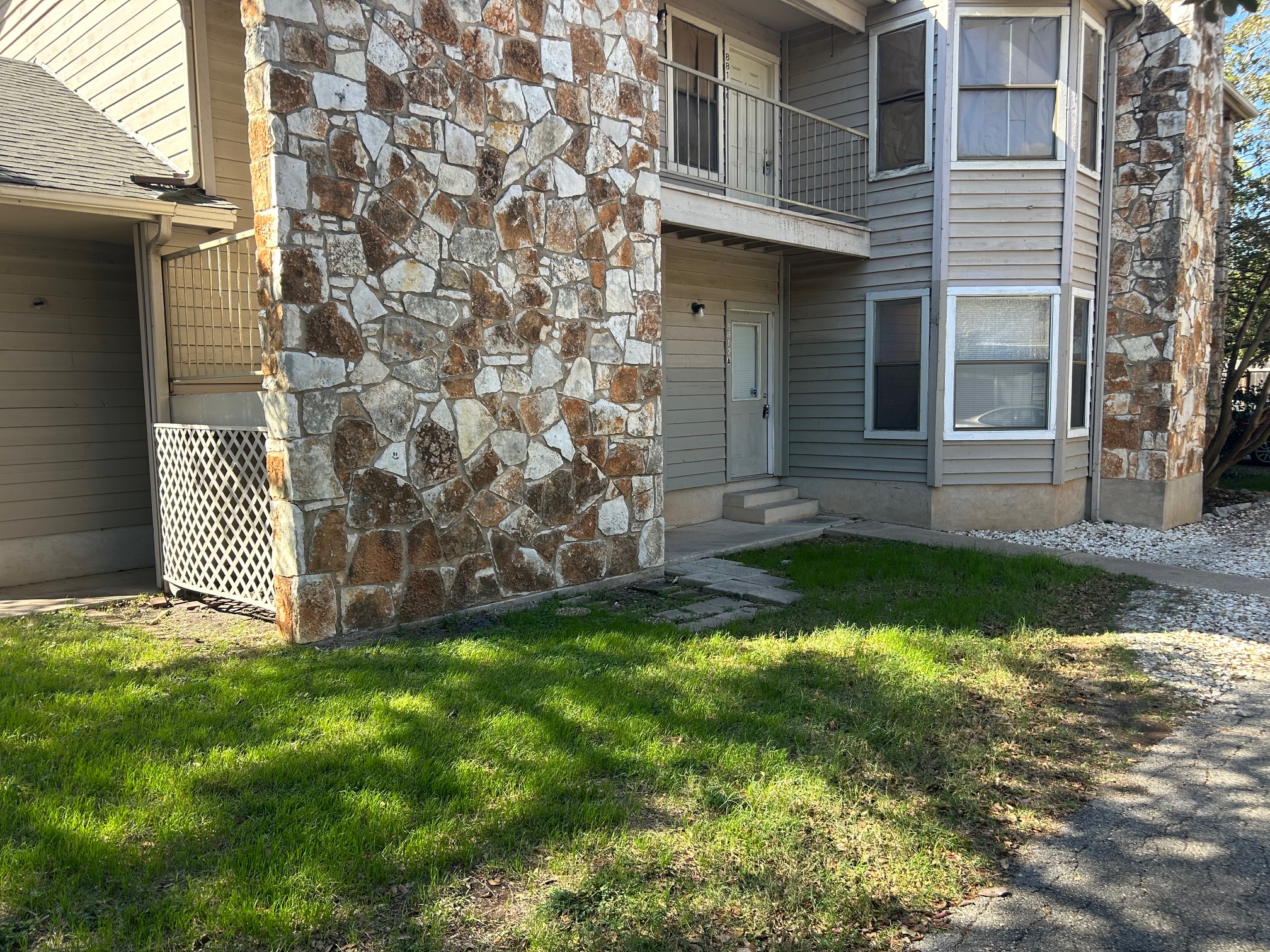 8812 Schick Road, Unit C Austin, TX 78729 - Photo 2 of 12 Property entrance featuring stone siding and a lawn