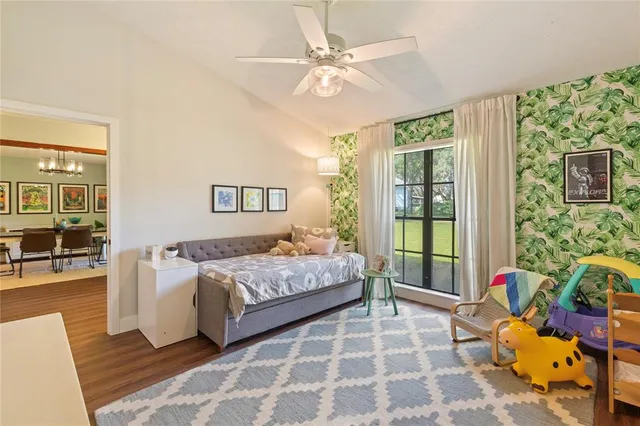 a view of a bedroom with baby bed lounge chair and a chandelier