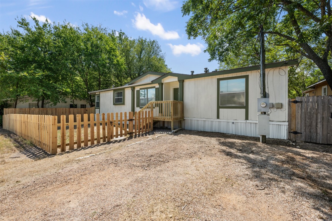 a view of a house with a wooden fence and a large tree