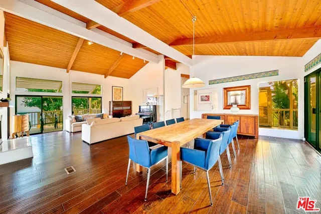 a dining room with wooden floor and large windows