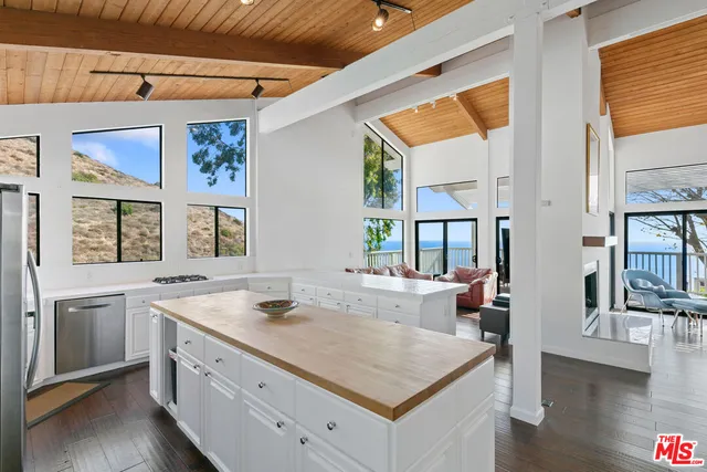 a view of a kitchen counter top space with stainless steel appliances wooden floor and large windows