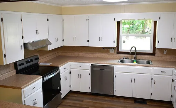 a kitchen with cabinets appliances a sink and a window