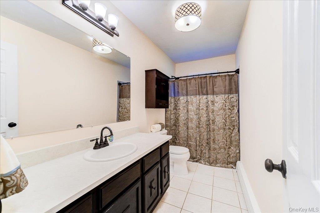 60 Sutton Park Road Poughkeepsie, NY 12603 - Photo 18 of 30 Bathroom featuring a dark wood finish vanity with a solid surface countertop, white ceramic tile flooring, and a built-in wall cabinet