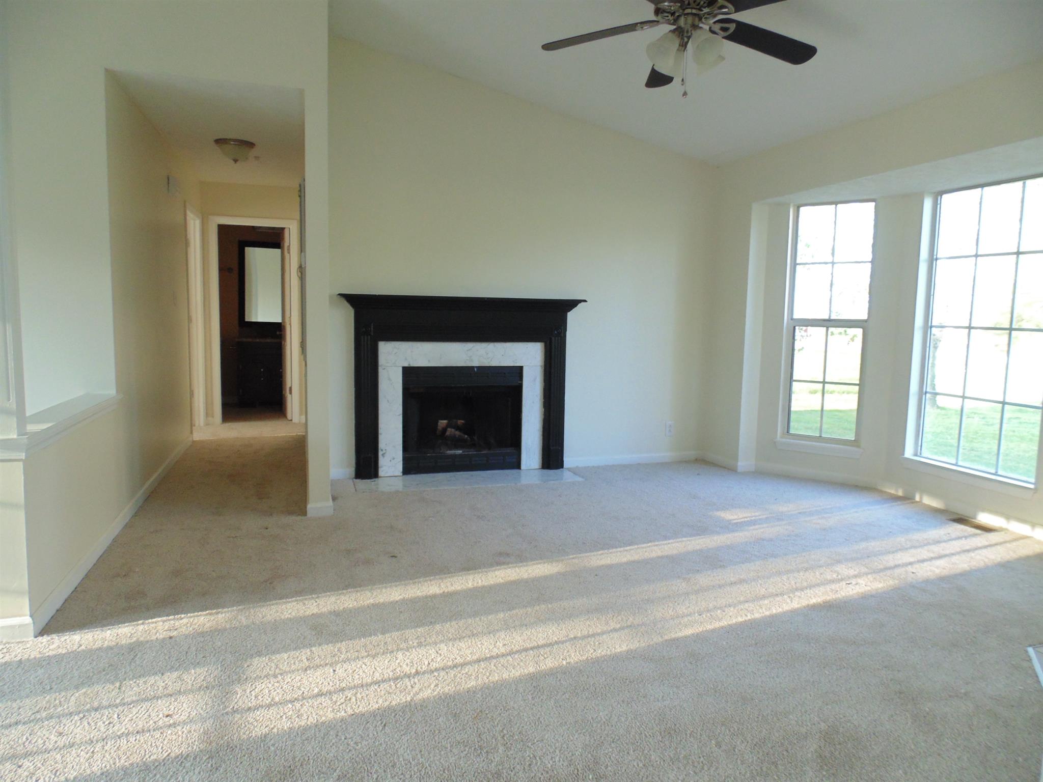 8671 Pembroke Oak Grove Road Oak Grove, KY 42262 - Photo 2 of 11 an empty room with a fireplace and windows