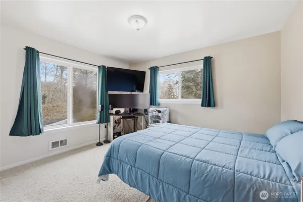 a bedroom with a bed a large window and flat screen tv