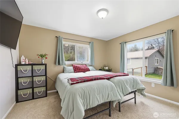 a bedroom with a bed a painting on the wall and a large window