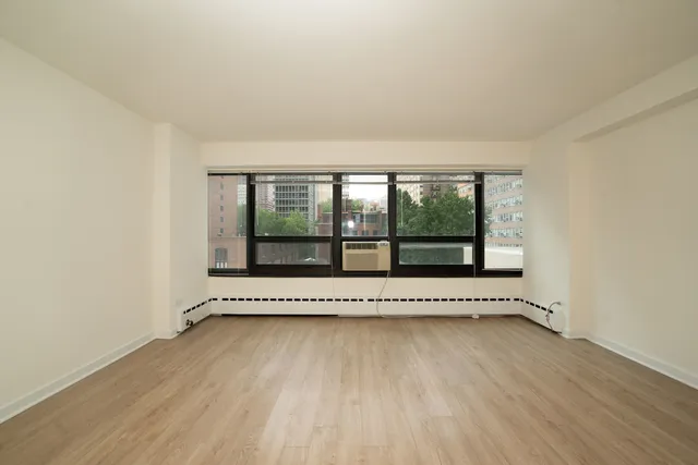 a view of an empty room with a window and wooden floor