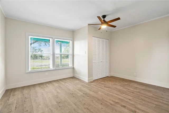 a view of an empty room with wooden floor and a window