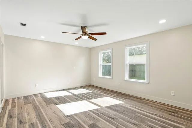 a view of empty room with wooden floor and fan