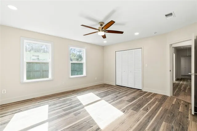 a view of empty room with wooden floor and fan