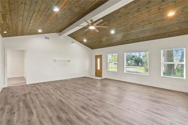 a view of an empty room with a window and wooden floor