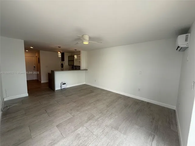 an empty room with a kitchen and chandelier fan