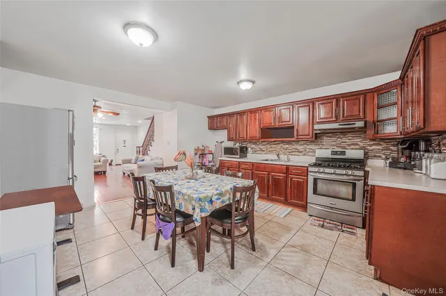 a open kitchen with stainless steel appliances granite countertop a stove a sink a refrigerator dining table and chairs