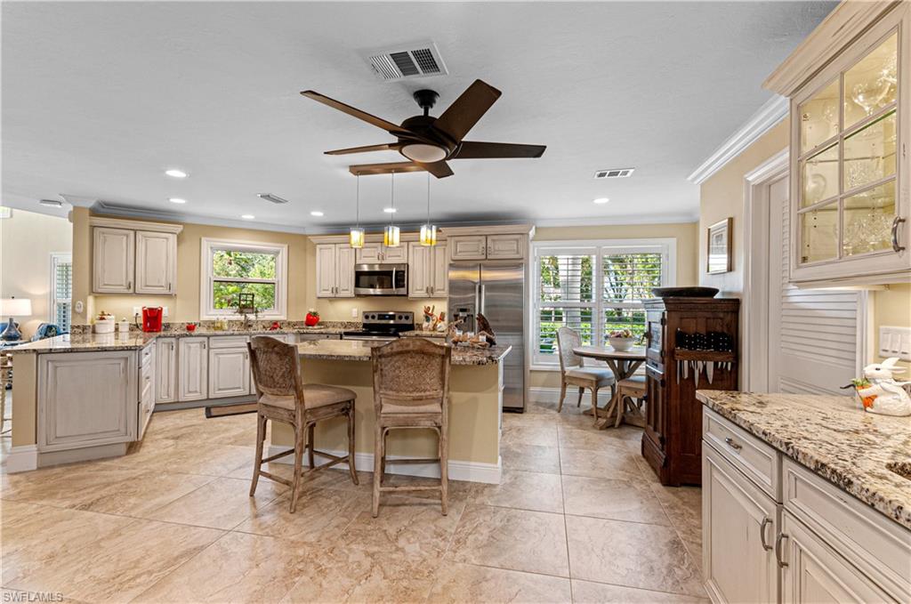 4022 Crayton Road Naples, FL 34103 - Photo 9 of 28 a kitchen with stainless steel appliances kitchen island granite countertop a table chairs sink and cabinets