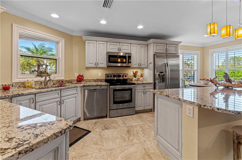 4022 Crayton Road Naples, FL 34103 - Photo 10 of 28 a kitchen with stainless steel appliances kitchen island granite countertop a stove sink and cabinets