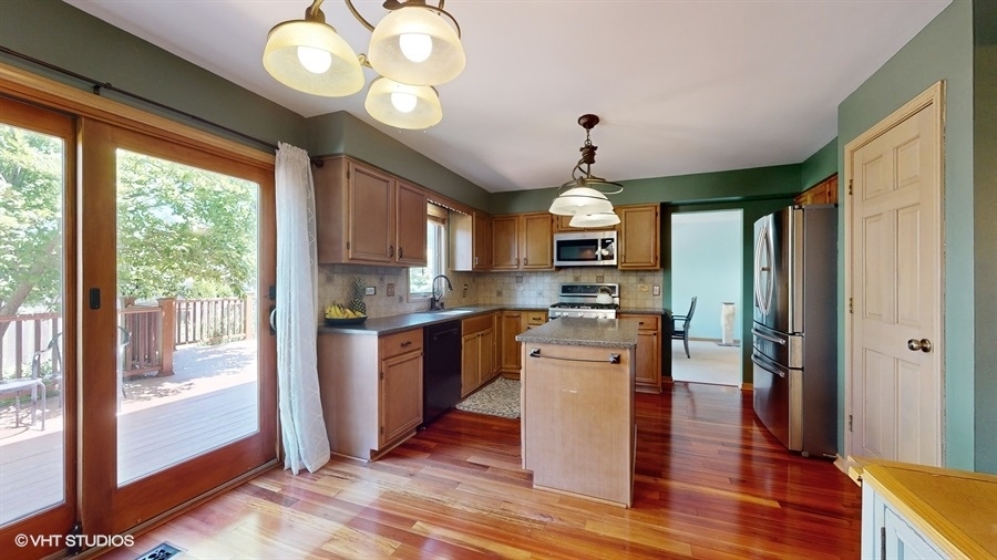 545 Abbey Road Bartlett, IL 60103 - Photo 9 of 28 a kitchen with stainless steel appliances granite countertop a refrigerator a sink dishwasher a stove and a dining table with wooden floor