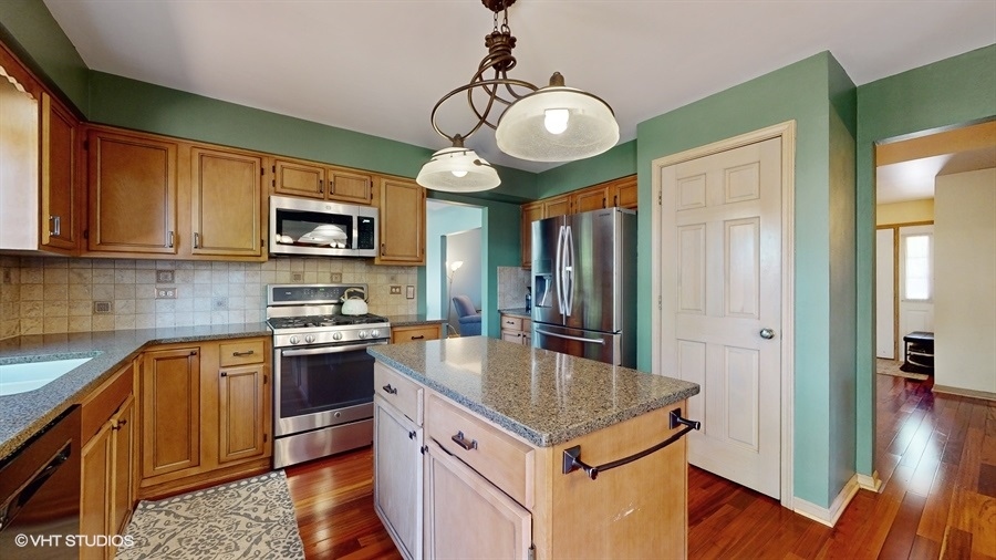 545 Abbey Road Bartlett, IL 60103 - Photo 10 of 28 a kitchen with kitchen island granite countertop stainless steel appliances a stove top oven a sink dishwasher and microwave with wooden floor