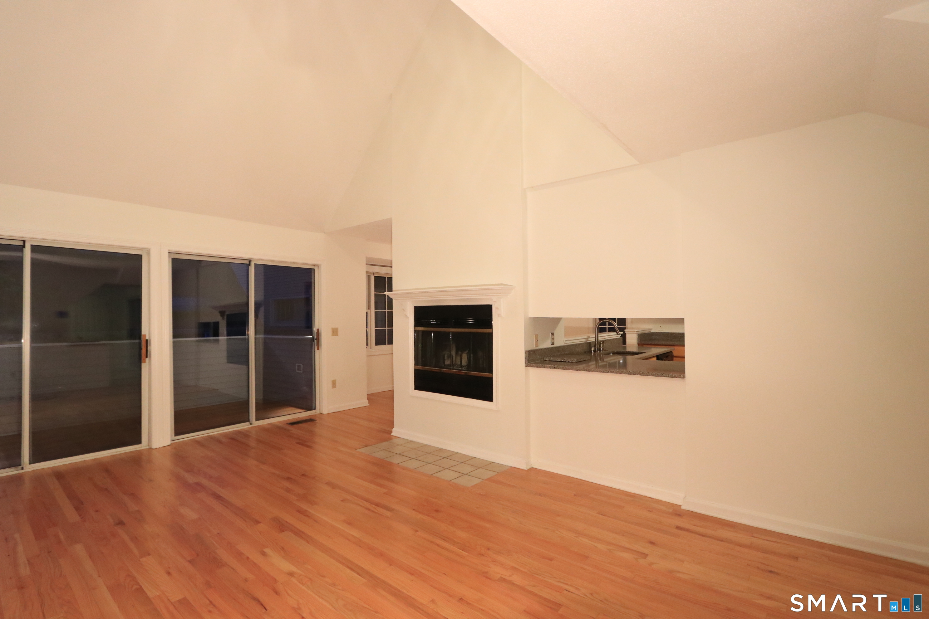 50 Wilton Crest Road, Unit 50 Wilton, CT 06897 - Photo 5 of 31 Living room with fireplace and vaulted ceiling, sliders open to a deck