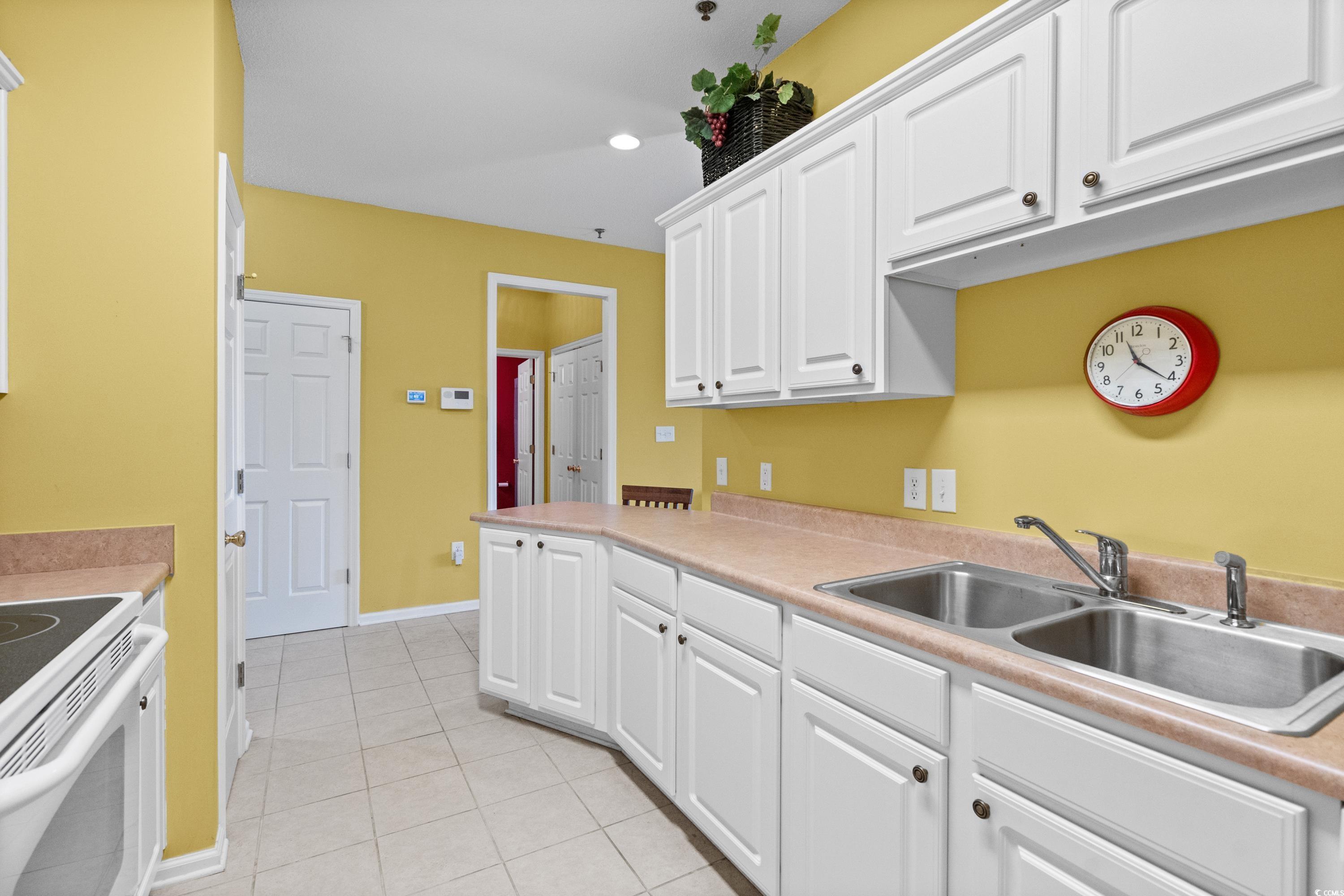 2050 Cross Gate Boulevard, Unit 303 Myrtle Beach, SC 29575 - Photo 14 of 35 Kitchen with light tile patterned floors, white cabinetry, sink, and white electric stove