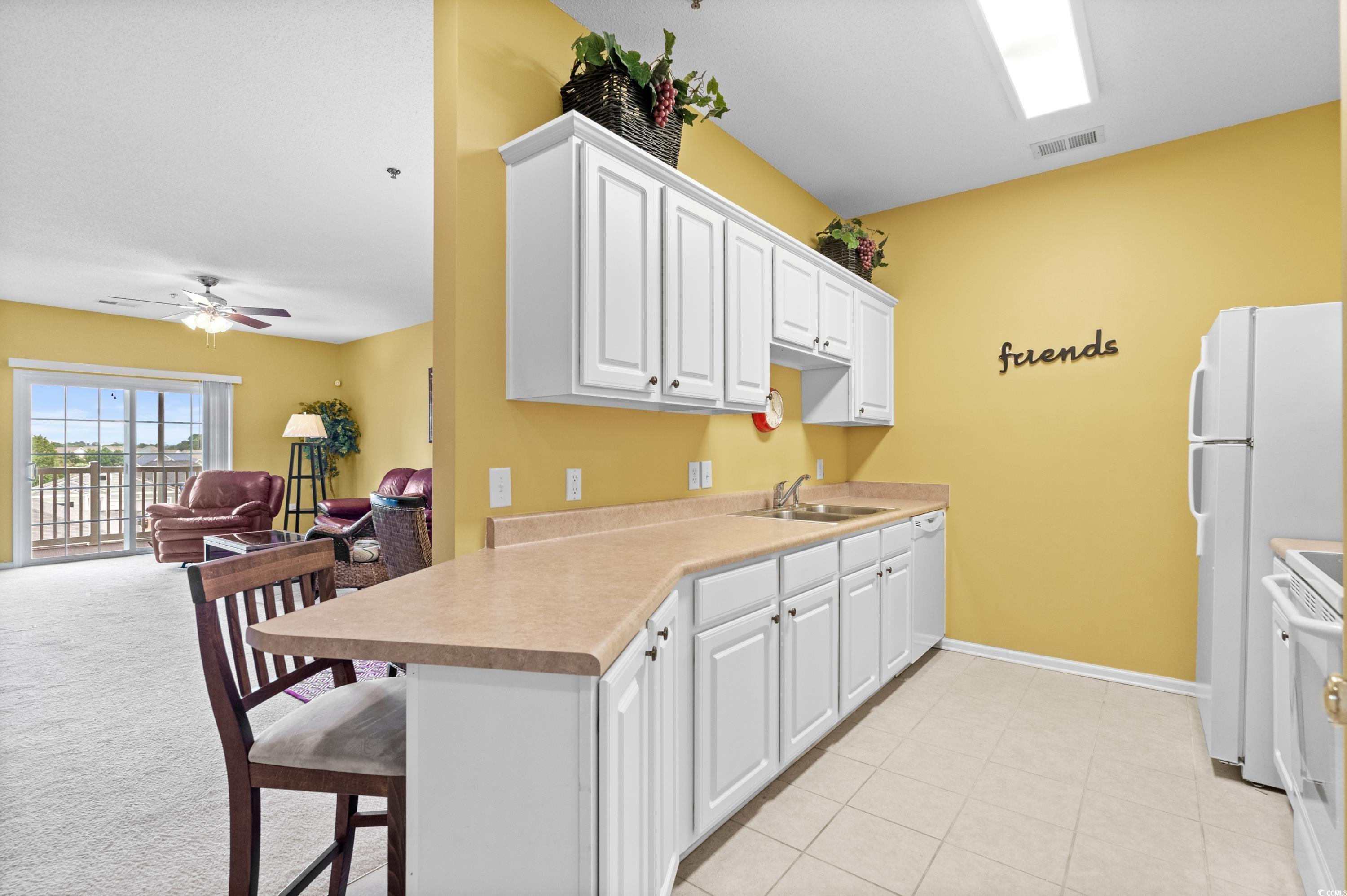 2050 Cross Gate Boulevard, Unit 303 Myrtle Beach, SC 29575 - Photo 17 of 35 Kitchen featuring white cabinets, ceiling fan, white appliances, and light carpet