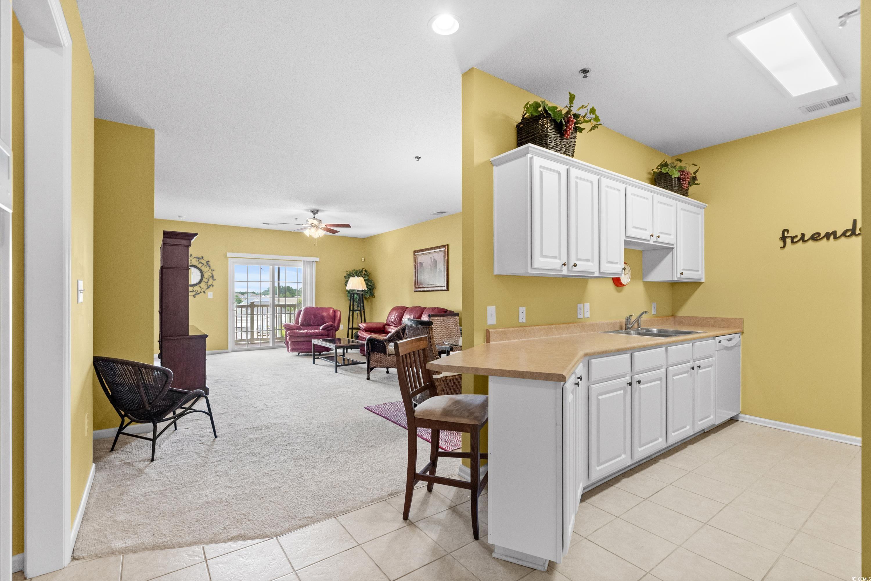 2050 Cross Gate Boulevard, Unit 303 Myrtle Beach, SC 29575 - Photo 4 of 35 Kitchen with ceiling fan, sink, kitchen peninsula, and white cabinets