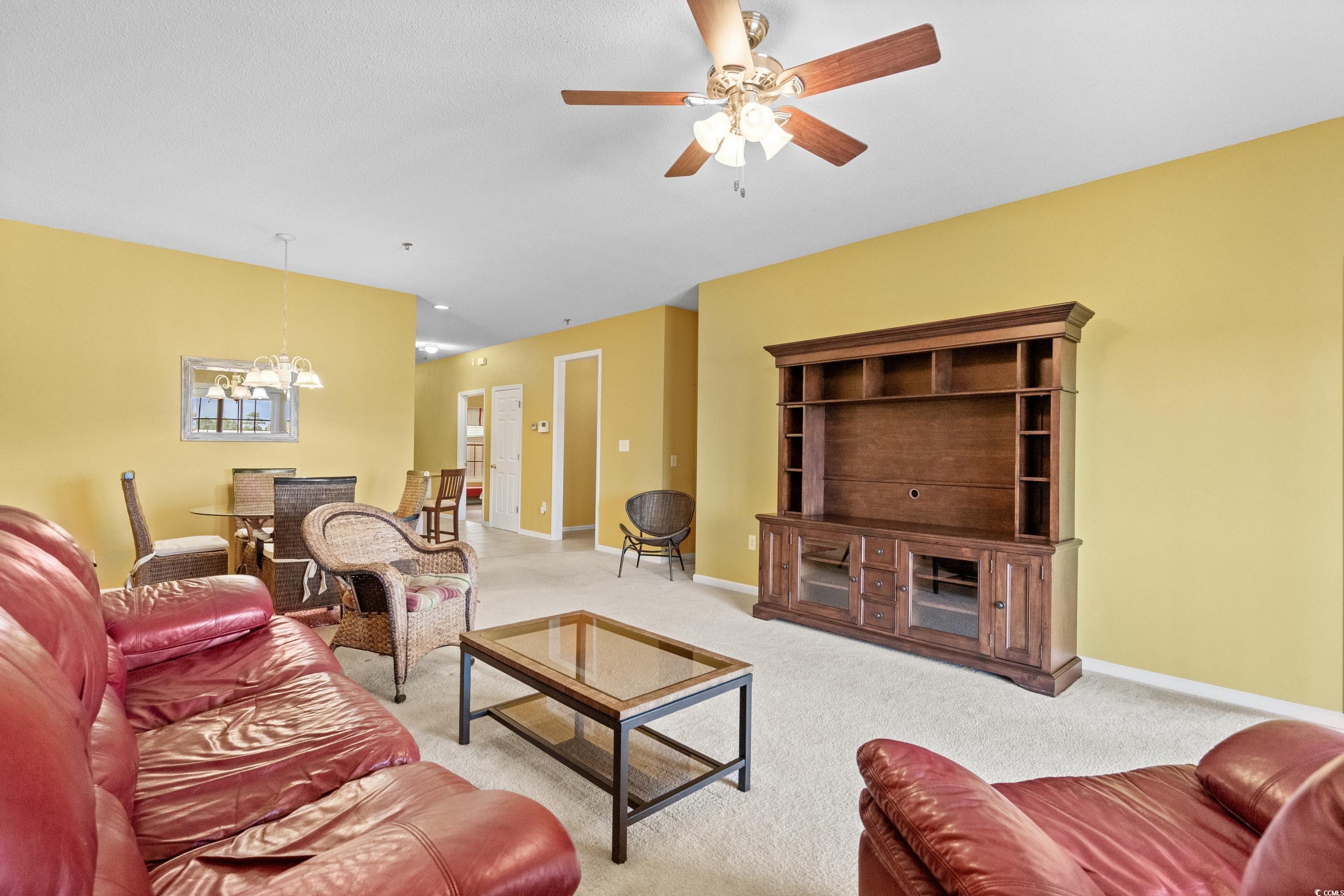 2050 Cross Gate Boulevard, Unit 303 Myrtle Beach, SC 29575 - Photo 8 of 35 Carpeted living room with ceiling fan with notable chandelier