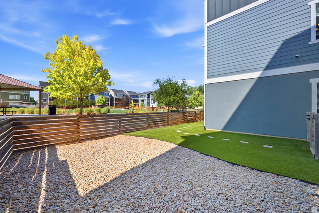 862 Founders Point Lane South Midvale, UT 84047 - Photo 32 of 45 Blue siding exterior, wood horizontal slat fencing, gravel ground cover, artificial turf, and a covered outdoor structure
