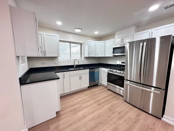a kitchen with granite countertop white cabinets and stainless steel appliances
