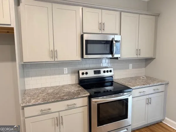 a kitchen with granite countertop white cabinets and stainless steel appliances