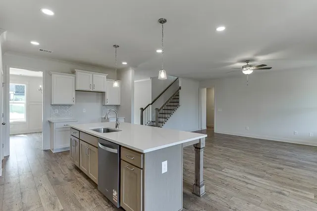 a kitchen with a stove a sink and wooden floor