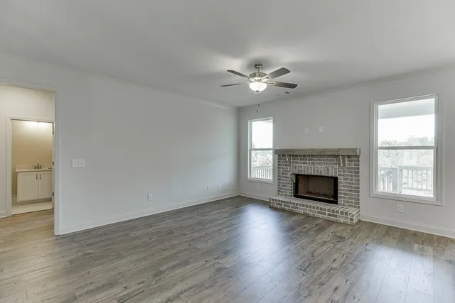 an empty room with wooden floor fireplace and windows