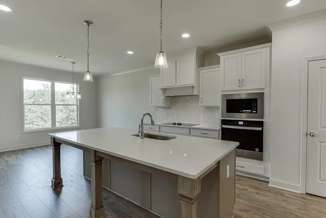 a kitchen with a sink a stove a microwave and wooden floor
