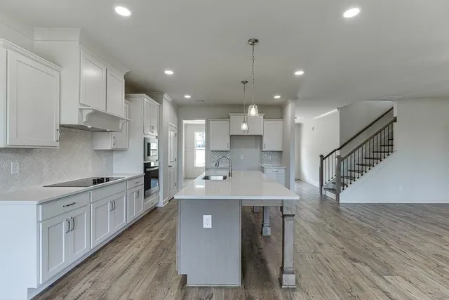 a kitchen with kitchen island a sink and a stove top oven