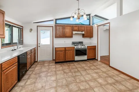 a large kitchen with stainless steel appliances granite countertop a stove a sink dishwasher a refrigerator and a microwave