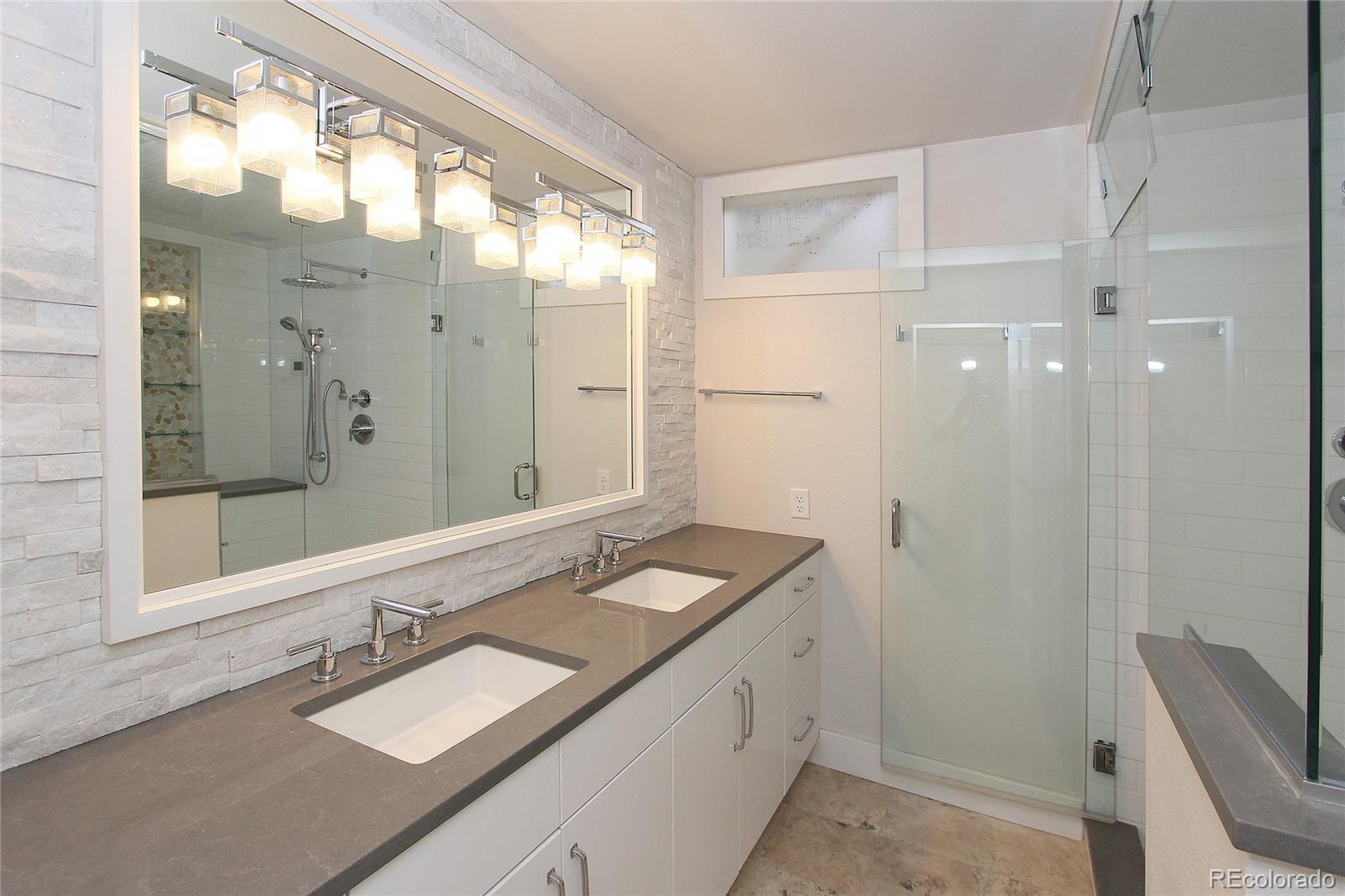 6250 Waterfall Loop Manitou Springs, CO 80829 - Photo 18 of 36 a bathroom with a granite countertop double vanity sink a mirror and a shower