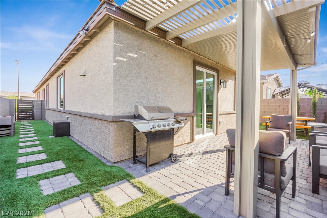9398 Noble Fir Rdg Court Las Vegas, NV 89143 - Photo 30 of 36 An inviting backyard retreat features a paved patio, a covered pergola, and a lush green pathway.